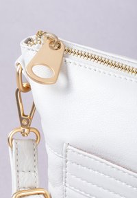 White leather handbag featuring gold hardware, a zip closure, and a quilted front pocket. Includes a detachable strap and clasp.