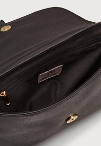 Wnętrze czarnej syntetycznej torebki z kieszenią na zamek błyskawiczny, gładką teksturą i złoconym zatrzaskiem. Etykieta z napisem "ANNA FIELD".