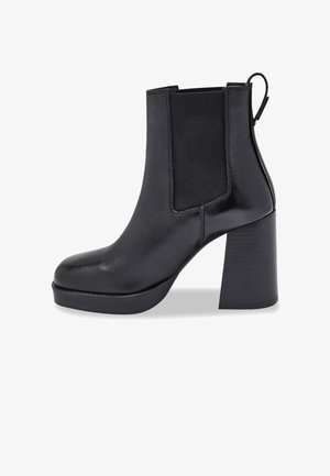 Stivale alla caviglia in pelle nera con pannelli elastici laterali, punta arrotondata e tacco alto chunky. Presenta una finitura testurizzata e una linguetta sul retro.