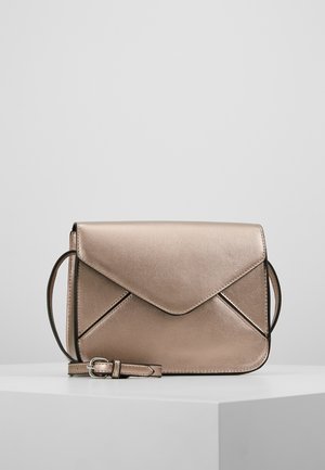 Petit sac bandoulière en métal rose doré avec rabat en forme d'enveloppe et sangle réglable reposant sur une surface blanche.