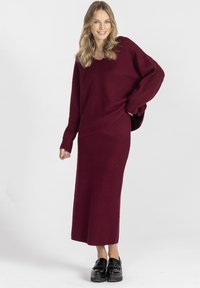 Burgundowa, prążkowana dzianinowa bluzka i dopasowana maks spódnica, luźny krój z długimi rękawami i subtelną fakturą, połączone z błyszczącymi, czarnymi, chunky butami.