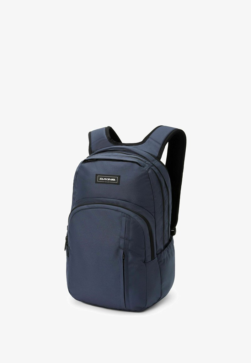 Mörkblå ryggsäck av hållbart tyg, med justerbara vadderade remmar, två framfickor med dragkedja och en huvudfack med kurvig design.