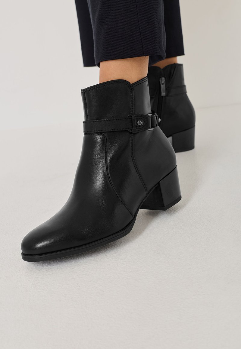 Melnas ādas potītes botas ar smailu pirkstu, ar sānu rāvējslēdzēju un regulējamu siksniņu ar sprādzi. Bloku papēdis.