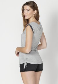 Sivý top s krátkym rukávom a textúrovanými ramennými akcentmi, doplnený čiernymi šortkami. Mäkká tkanina, voľný strih.