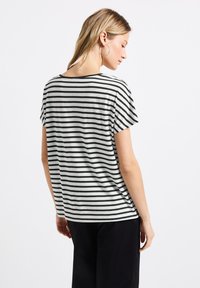 Camiseta de rayas en blanco y negro con mangas cortas, escote redondeado y un corte relajado, hecha de material de algodón suave.