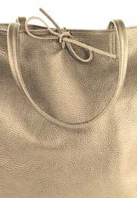 Sac fourre-tout en cuir gris métallisé avec une finition texturée, doté de deux poignées rondes et d'un détail de fermeture nouée en haut.