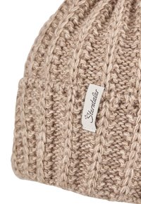 Beige knitted woolen beanie with vertical cable-knit pattern and a sewn white fabric label with brand name "Sterntaler."