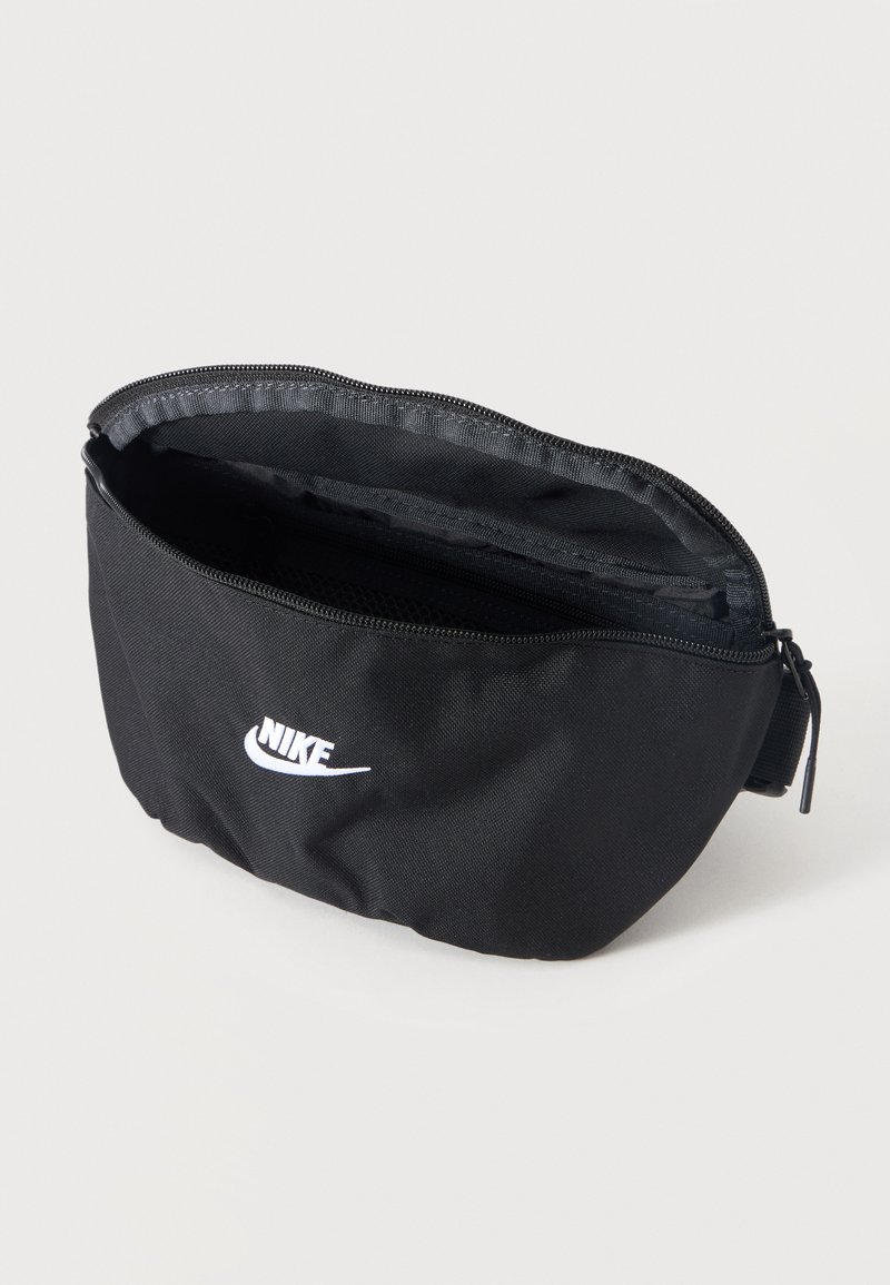 Black Nike waist bag with open zipper and white swoosh logo on front, displayed against a plain light background.
