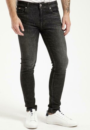 Czarne dżinsy slim fit z delikatną teksturą, z przodu zapinane na guzik, pięć kieszeni, w połączeniu z białymi trampkami.
