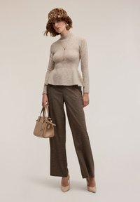 Maglione beige con baschina, pantaloni a quadri marroni, tacchi color nudo, cappello a stampa leopardo, collana d'oro e borsa dal design strutturato con dettagli.