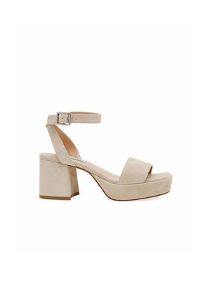 Sandali con tacco in suede beige, dotati di un robusto tacco a blocco, punta aperta, un'ampia fascia sul piede e una cinghia regolabile alla caviglia con fibbia metallica.