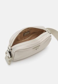 Beige nylon crossbody taske med lynlåslukning, logoeksel og en glat tekstur. Indvendigt har den en brun foring og et lille logomærke.