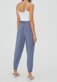 Ljusblå, elastiska joggerbyxor med tapered ben, sidofickor och ribbade vadder. Bärs med en vit spaghetti strap-topp.