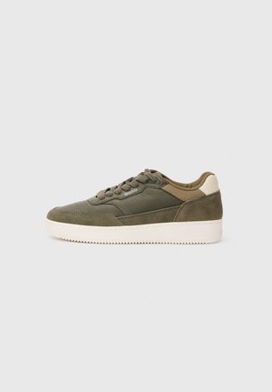 Basket en vert olive avec des panneaux en suède et en cuir perforé, présentant un accent beige au talon et une semelle en caoutchouc blanche.