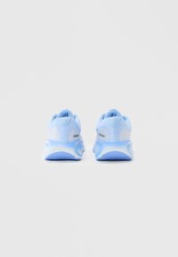 Un par de zapatillas deportivas de color azul claro vistas desde atrás, con malla blanca y suelas redondeadas, sobre un fondo claro y liso.