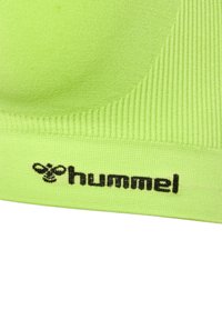 Jasnozielony stanik sportowy wykonany z gładkiego, elastycznego materiału, z prążkowaną fakturą i wyraźnym czarnym logo "hummel" na pasku.