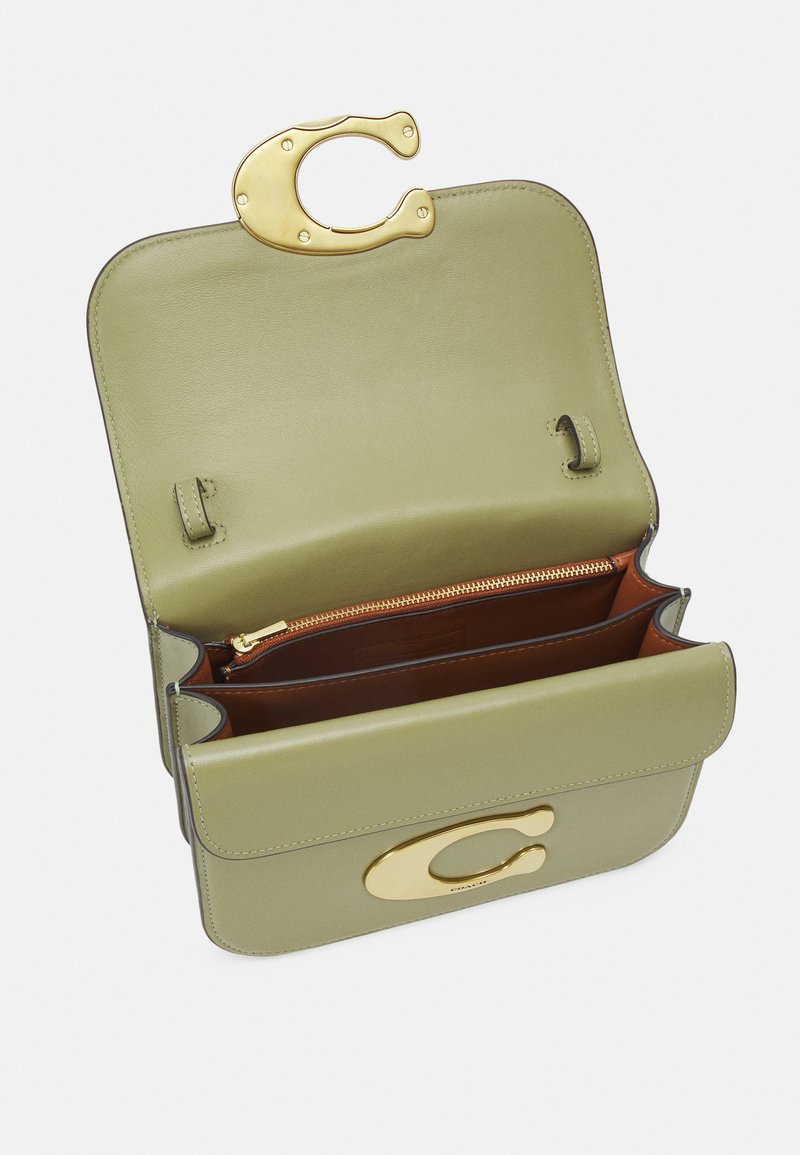 Olivengrüne Lederhandtasche mit einem goldenen Verschluss. Verfügt über Innenfächer und ein Reißverschlussfach. Glatte Textur, strukturierte Form und minimalistisches Design.