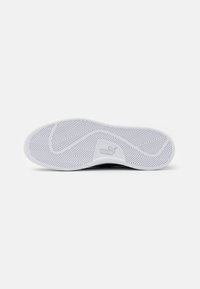 Biała podeszwa sneakersów z wzorem w jodełkę; zawiera uformowany obszar z logo Pumy. Gładka tekstura, zaokrąglone krawędzie i brak widocznego zużycia.