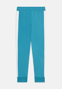 Turkosa träningsbyxor med en stretchy midja, smal passform och vita sidopaneler. Texturerat tyg med ribbade ankle cuffs.