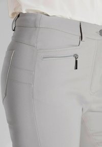 Lichtgrijze broek met een soepele textuur, voorzien van een zijzak met rits, subtiele stikseldetails en een aansluitend ontwerp.