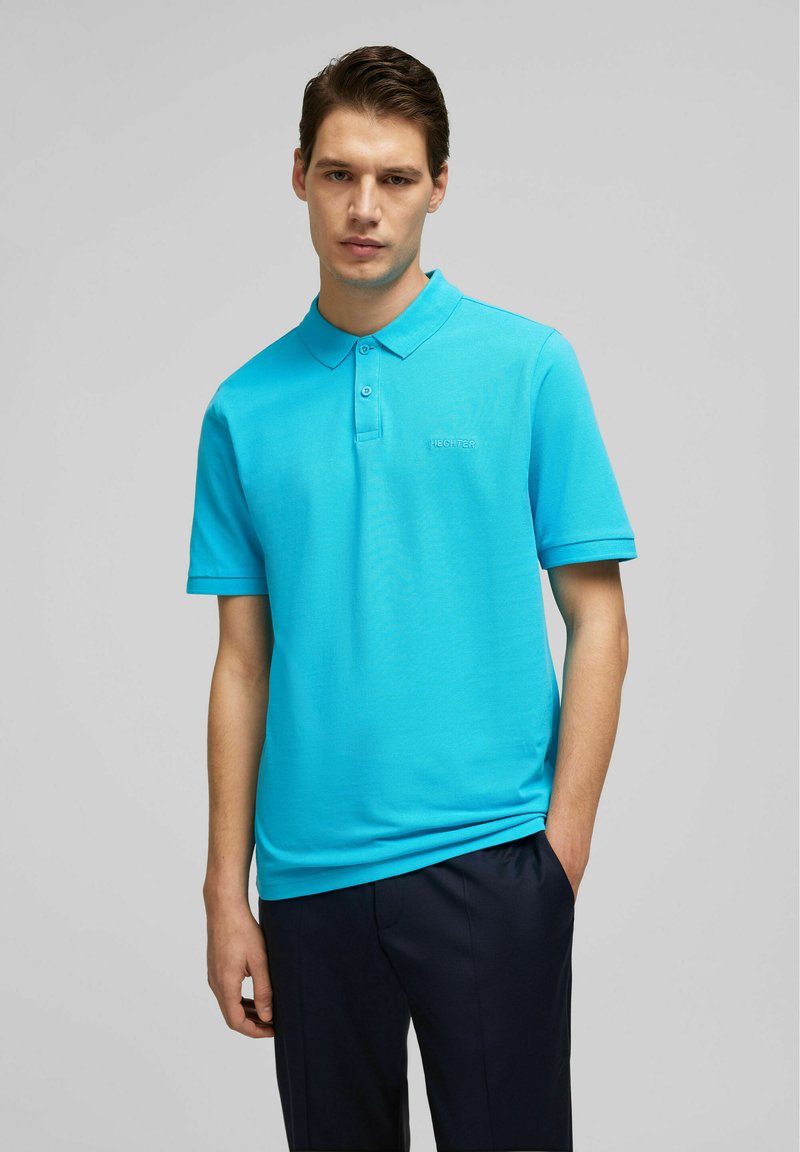 Turquoise polo shirt gemaakt van een gladde, lichte stof. Beschikt over een kraag, een drieknoopsluiting en een geborduurd logo op de borst.