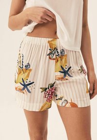 Patterned shorts featuring a light fabric, elastic waistband, and colorful fruit and marine-themed illustrations on a striped background.