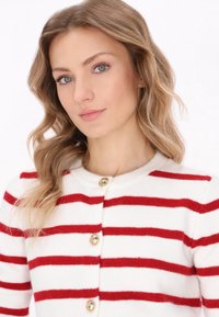 Red and white striped cardigan with a round neckline, featuring golden buttons down the front and a soft, textured fabric.