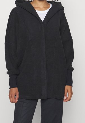 Sudadera de forro polar negra con cremallera frontal, ajuste holgado, hombros caídos y bolsillos laterales. Presenta una tela texturizada y una gran capucha.