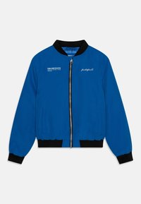 Niebieska kurtka typu bomber z czarnym prążkowanym kołnierzem i mankietami, zapinana na zamek z przodu, z bocznymi kieszeniami. Na lewej stronie klatki piersiowej znajduje się białe logo.