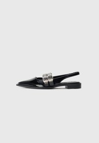 Musta patentoitu nahkainen tasapohjainen slingback-kengät, jossa on teräväkärkinen muoto ja kaksinkertaiset hopeiset soljet jalkapöydän kohdalla.