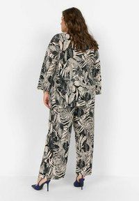 Zwart en beige 2-delige outfit met een oversized top en wijd uitlopende broeken met een tropisch bladmuster en lange mouwen.