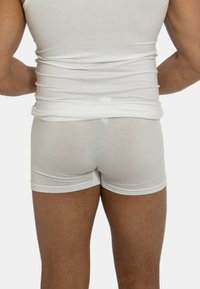 Canottiera bianca e boxer abbinati, realizzati in un tessuto morbido e elastico che adatta perfettamente alla figura grazie a una texture leggera.