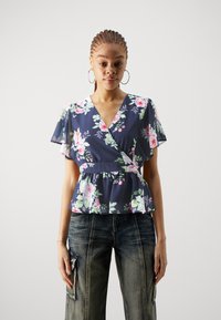 Marine blomstrete peplum-top med korte flatterende ermer, med nyanser av rosa og grønne blomster, v-hals og samlet midjedetalj.