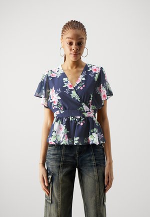 Top peplum floral en color navy con mangas cortas tipo volantes, que presenta tonos de flores en rosa y verde, escote en v y detalle de cintura fruncida.