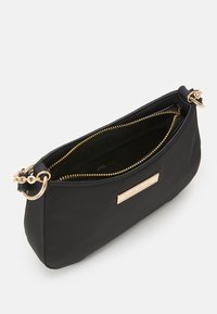 Czarna torebka nylonowa z złotą zamkiem, owalny kształt i łańcuchowy akcent na pasku. Zawiera logo producenta z przodu.