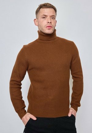 Pull en maille brun à col roulé avec une texture côtelée, un design ajusté et des manches longues. Le tissu est épais et élastique.
