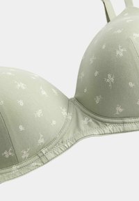 Light green padded bra with small white floral prints and adjustable straps on a white background.