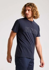 T-shirt en coton bleu marine arborant un audacieux graphique "SLAM" dans une teinte plus claire. Col rond classique et manches courtes. Texture douce et lisse.