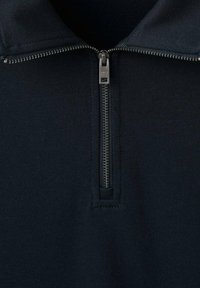 Tmavomodrá mikina na zips s krátkym golierom a kovovým zipsom. Materiál pôsobí hladko a mierne elasticky. Jednoduchý, jednofarebný dizajn.