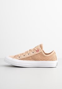 Sneaker in tela beige con texture intrecciata, suola in gomma bianca, punta tonda e occhielli argentati; presenta dettagli rosa vicino ai lacci.