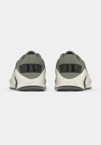 Chaussures de sport vertes à texture lisse, avec un logo Nike noir sur le talon et une semelle blanche avec des accents gris.