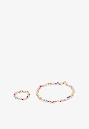 Fehér, virág alakú gyöngyökből készült karkötő és gyűrű, színes középpel és apró arany gyöngyökkel, fehér háttéren.