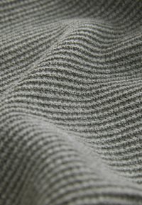 Tejido gris texturizado con un sutil patrón acanalado, mostrando pliegues y ondas. La superficie parece suave y ligeramente difusa.