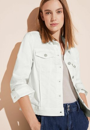 Weiße Jeansjacke mit gerolltem Kragen, zwei Brusttaschen und hochgekrempelten Ärmeln, kombiniert mit dunkelblauen hochgeschnittenen Jeans.