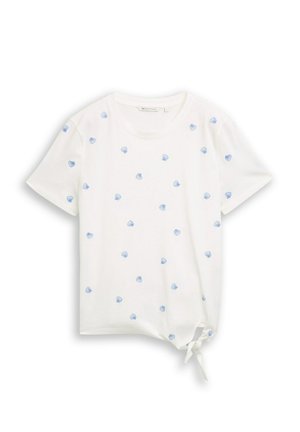 T-shirt blanc à manches courtes avec petits motifs coquillages bleus et un nœud sur le côté devant de l’ourlet.