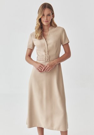Beige short-sleeve dress made of smooth fabric, featuring a collar, a button-down front, and a belted waist with a rectangular buckle.