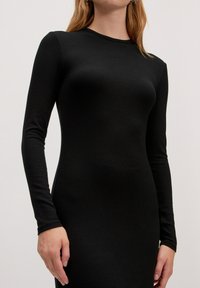 Zwarte jurk met lange mouwen gemaakt van ribbelstof. Slank model, ronde halslijn en naadloze constructie met zichtbare textuur.