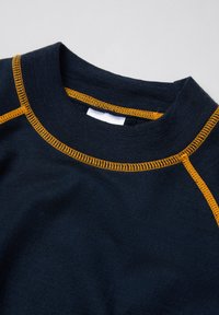 Marineblauwe gebreide shirt met ronde hals en oranje contraststiksels langs de kraag en schoudernaden op een effen achtergrond.