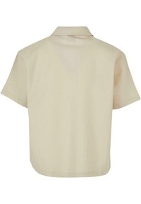 Beige kortermet skjorte med spredt krage, glatt tekstur, avrundet kant og ingen synlige mønstre eller dekorasjoner.