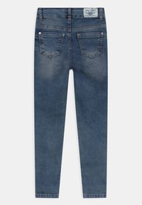 Vaqueros ajustados de denim azul oscuro, con un diseño clásico de cinco bolsillos, pasadores para cinturón y un ligero desvanecimiento en las piernas.
